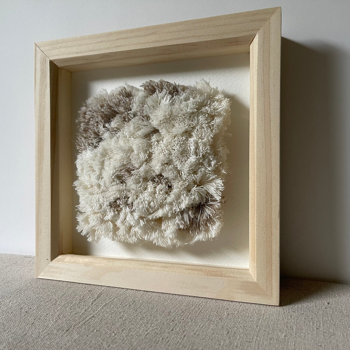 Cream and beige fluffy textured woven textile art in square natural wood deep box frame
