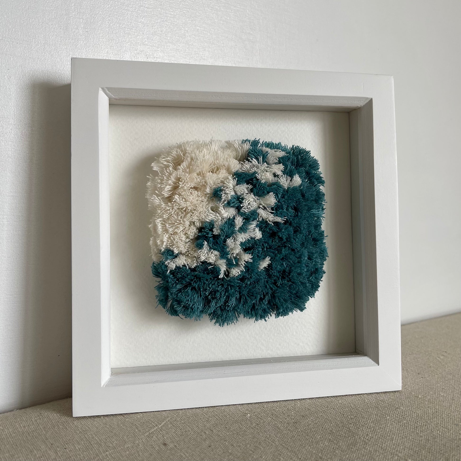 Ocean teal and cream fluffy textured woven  art in a square white painted wood box frame