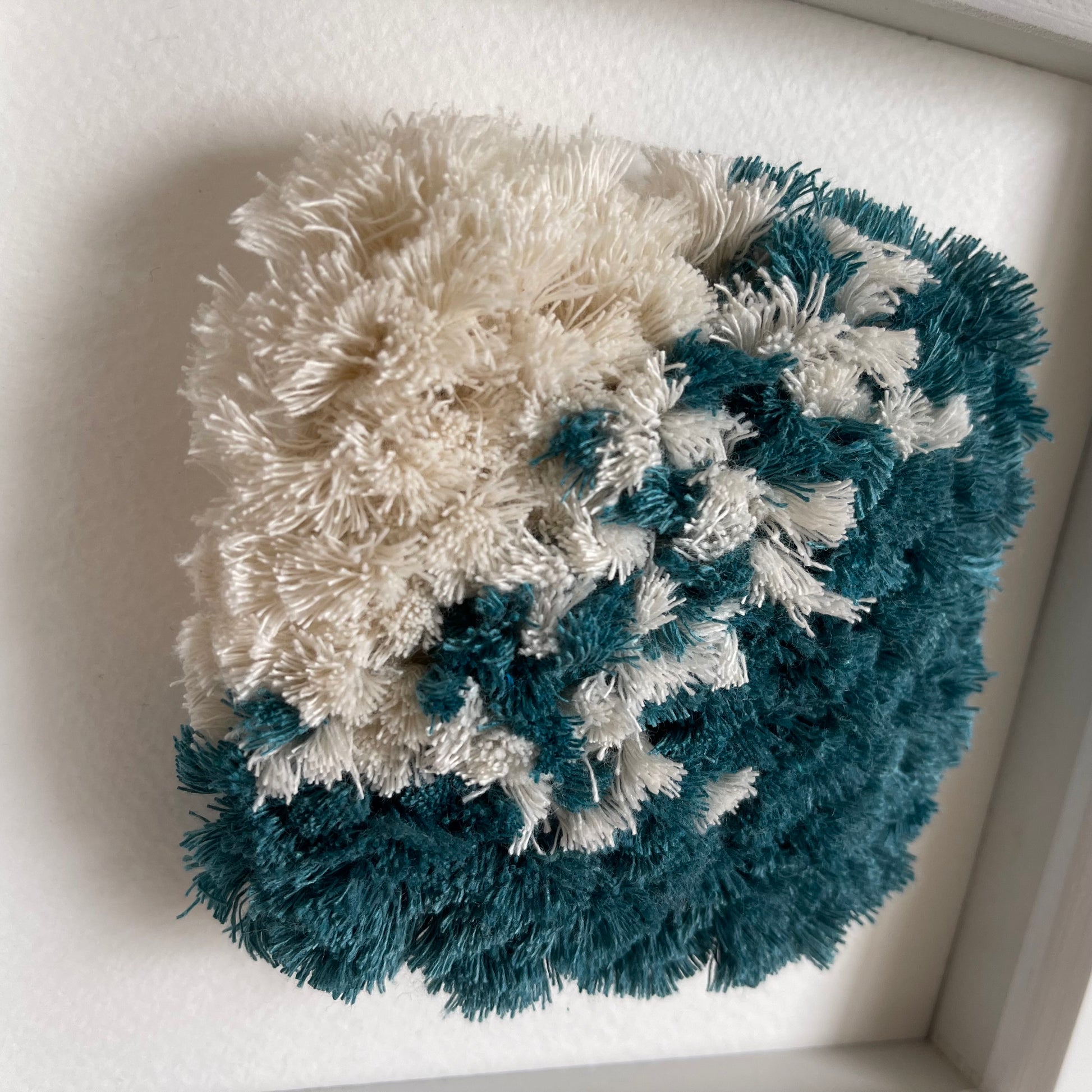Close up detail of  fluffy textured woven wall art in ocean teal and cream