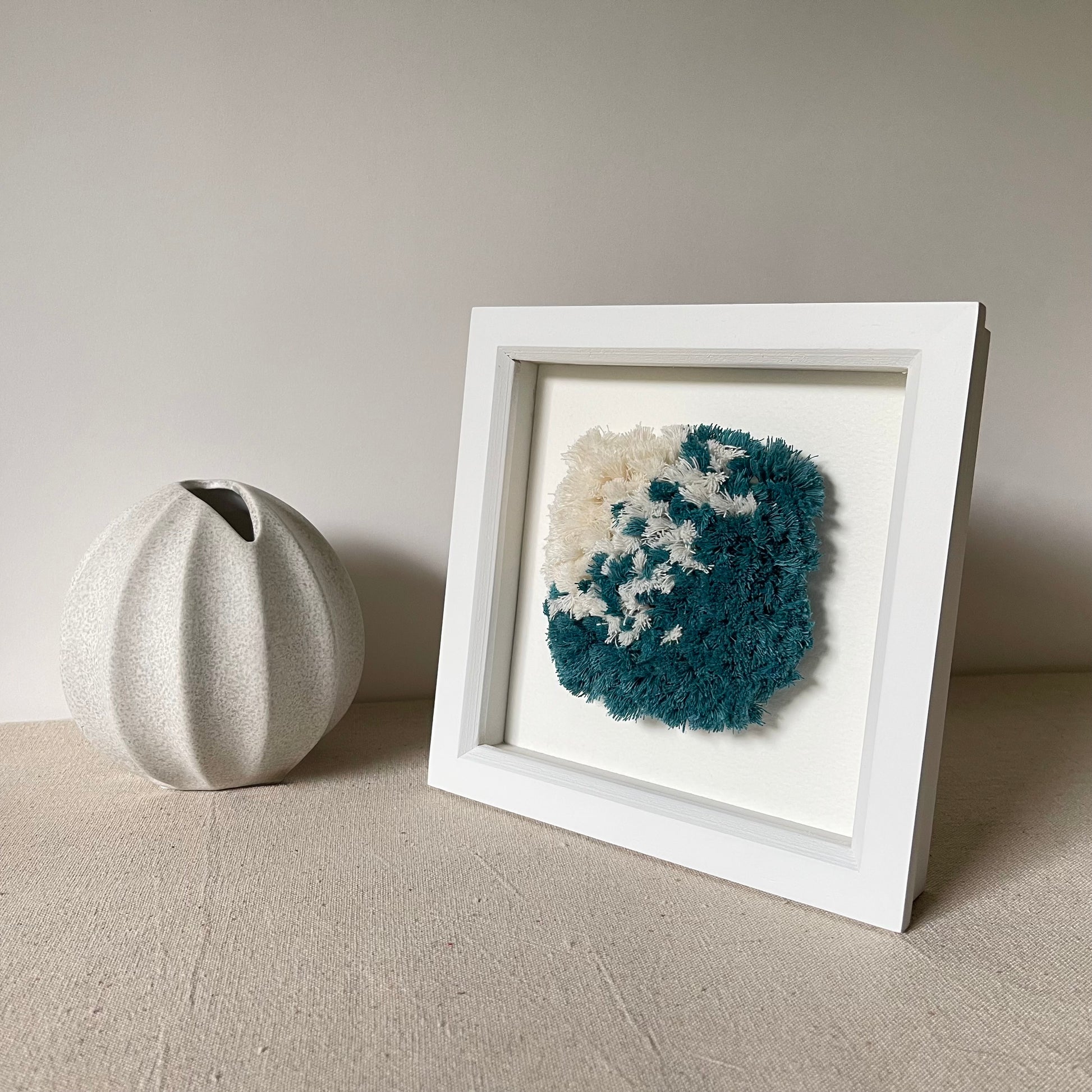 Ocean teal and cream fluffy textured woven wall art in a square white painted wood deep box frame
