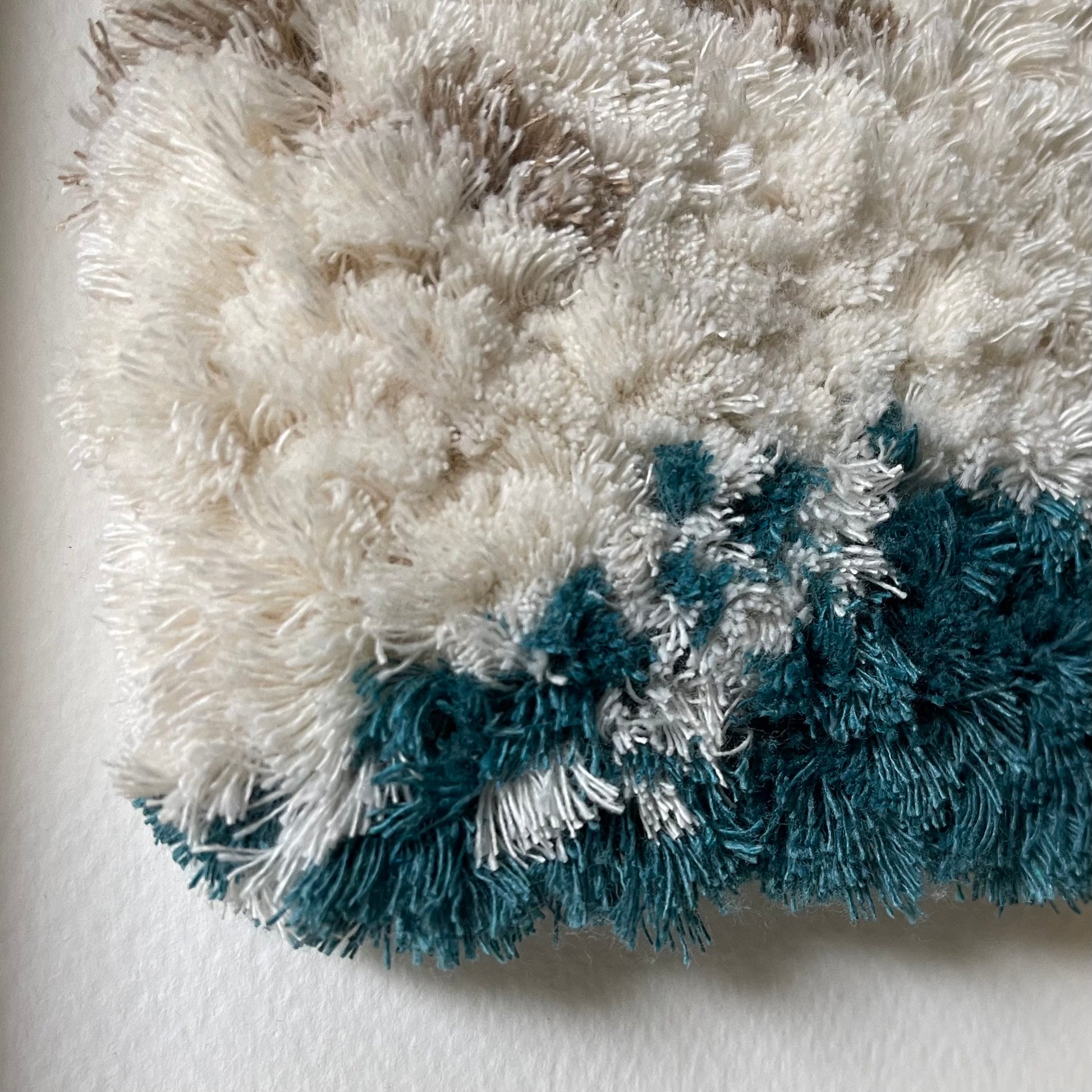 Close up detail of cream and ocean teal woven fluffy textured  art