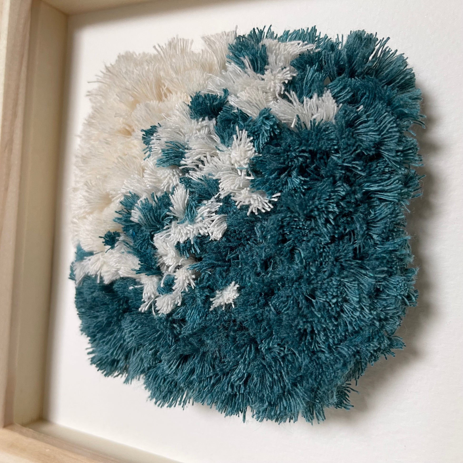 Close up detail of ocean teal and cream fluffy textured woven wall art