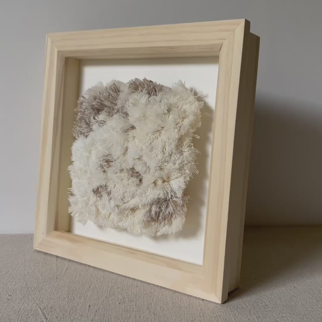 Video of cream and beige fluffy woven textile art in square natural wood deep box frame