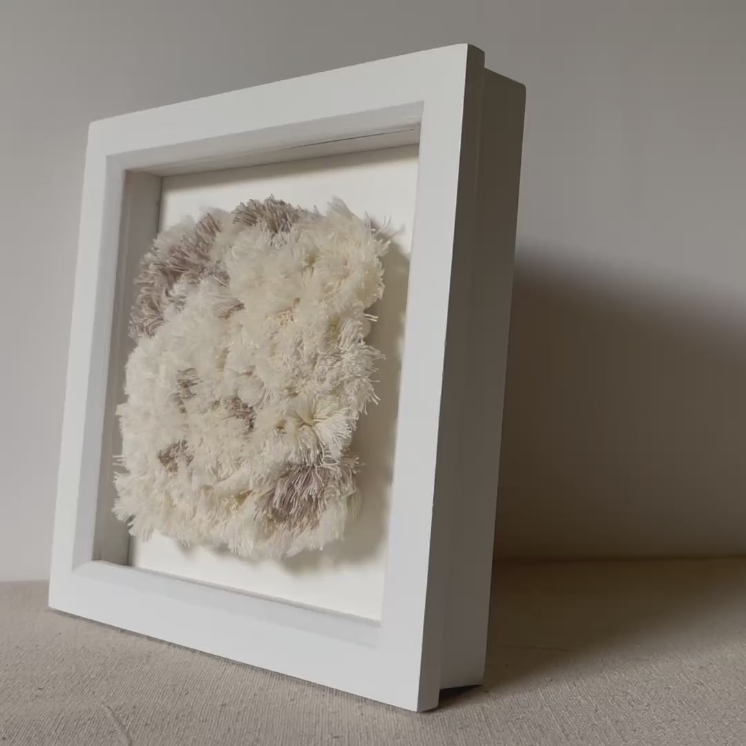 Video of cream and beige fluffy textured woven textile art in square white painted wood deep box frame