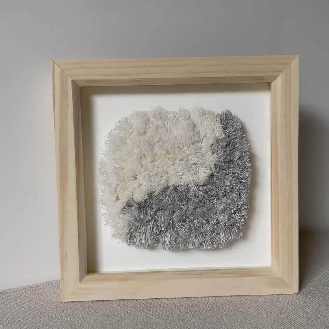 Video of blue and cream fluffy textured woven textile art in square natural wood deep box frame