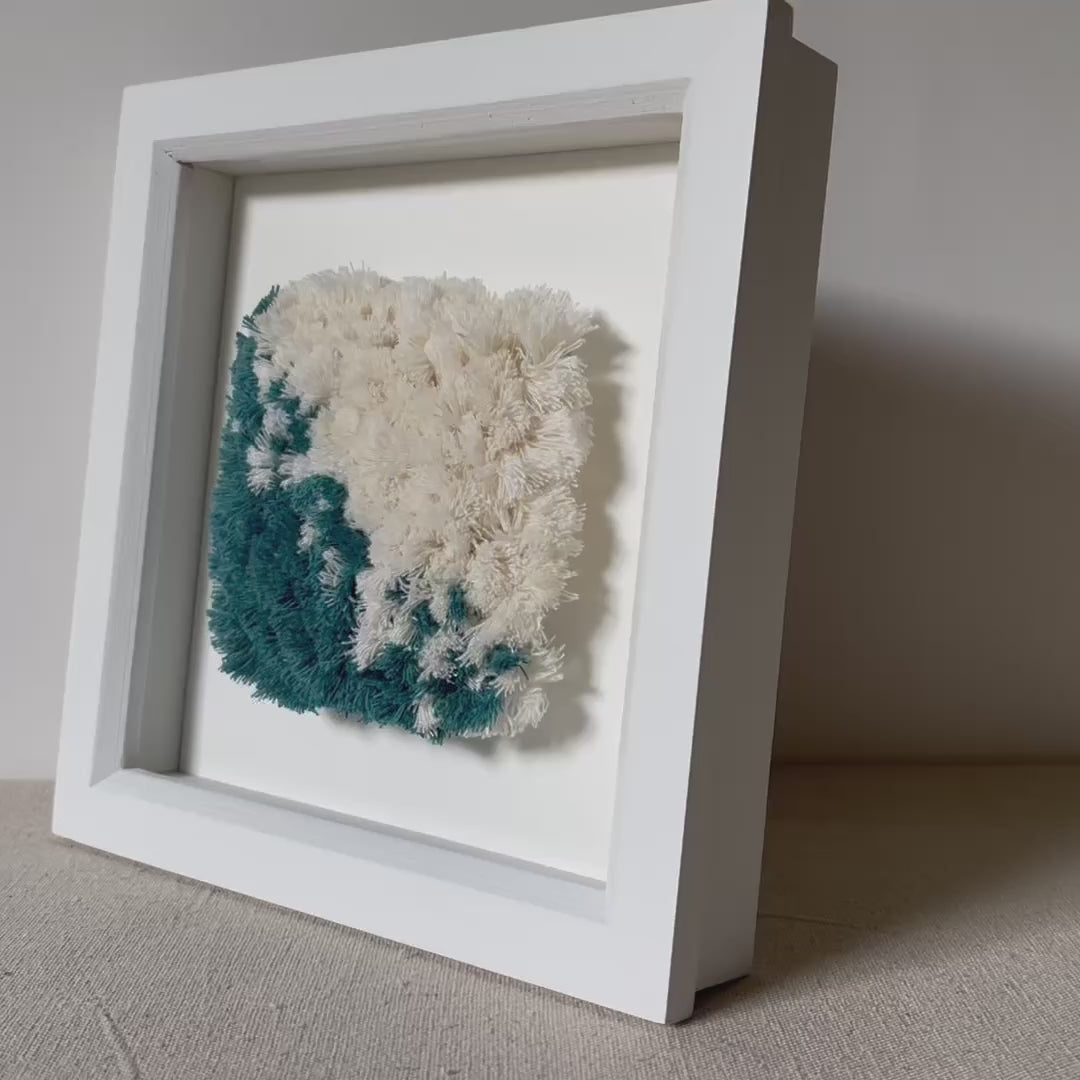 Video of teal and cream fluffy textured woven textile art in a square white painted wood deep box frame