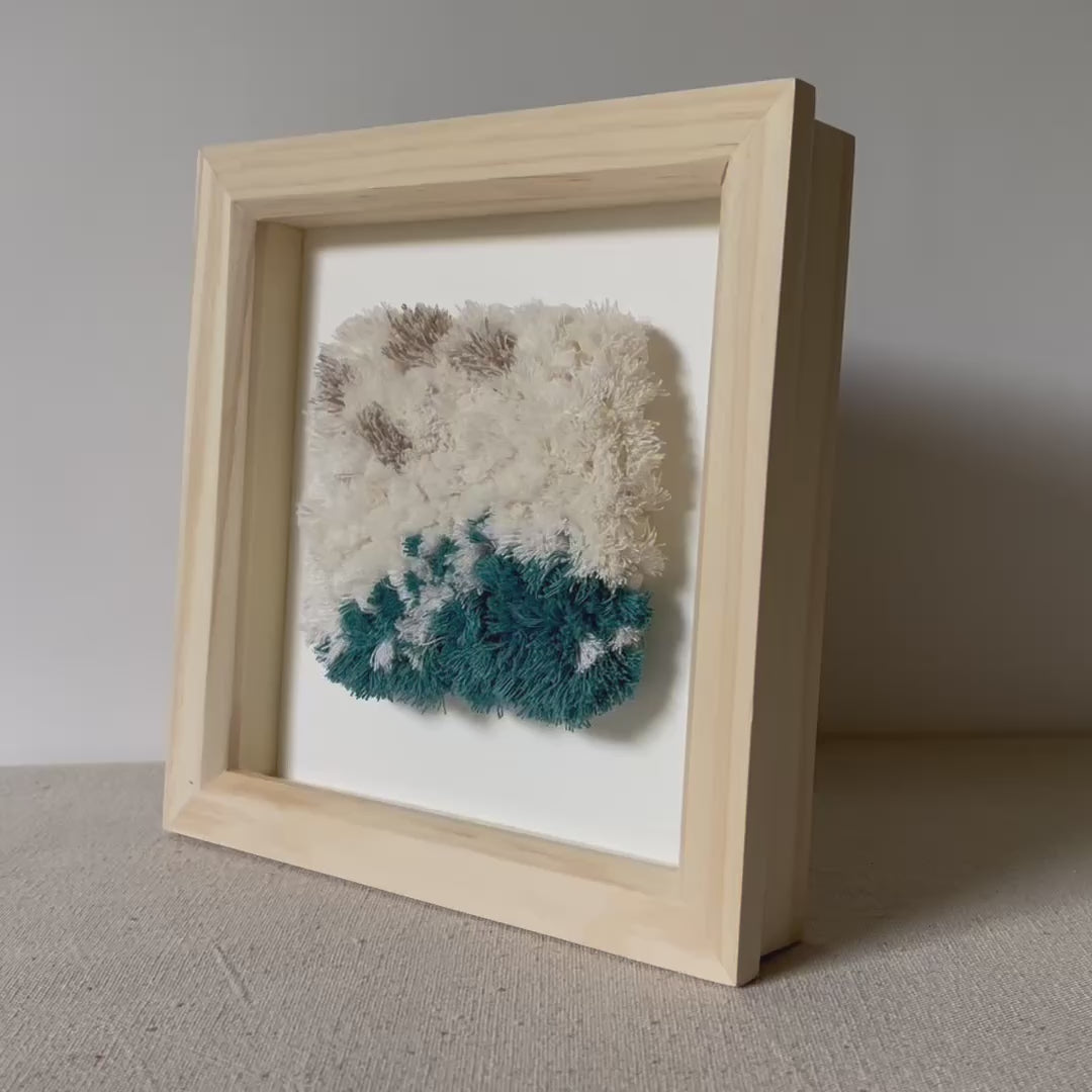 Video of cream and ocean teal woven fluffy textured  wall art in a square wood deep box frame