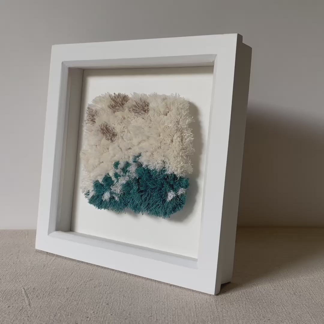 Video of cream and ocean teal woven fluffy textured  wall art in a square white painted wood deep box frame