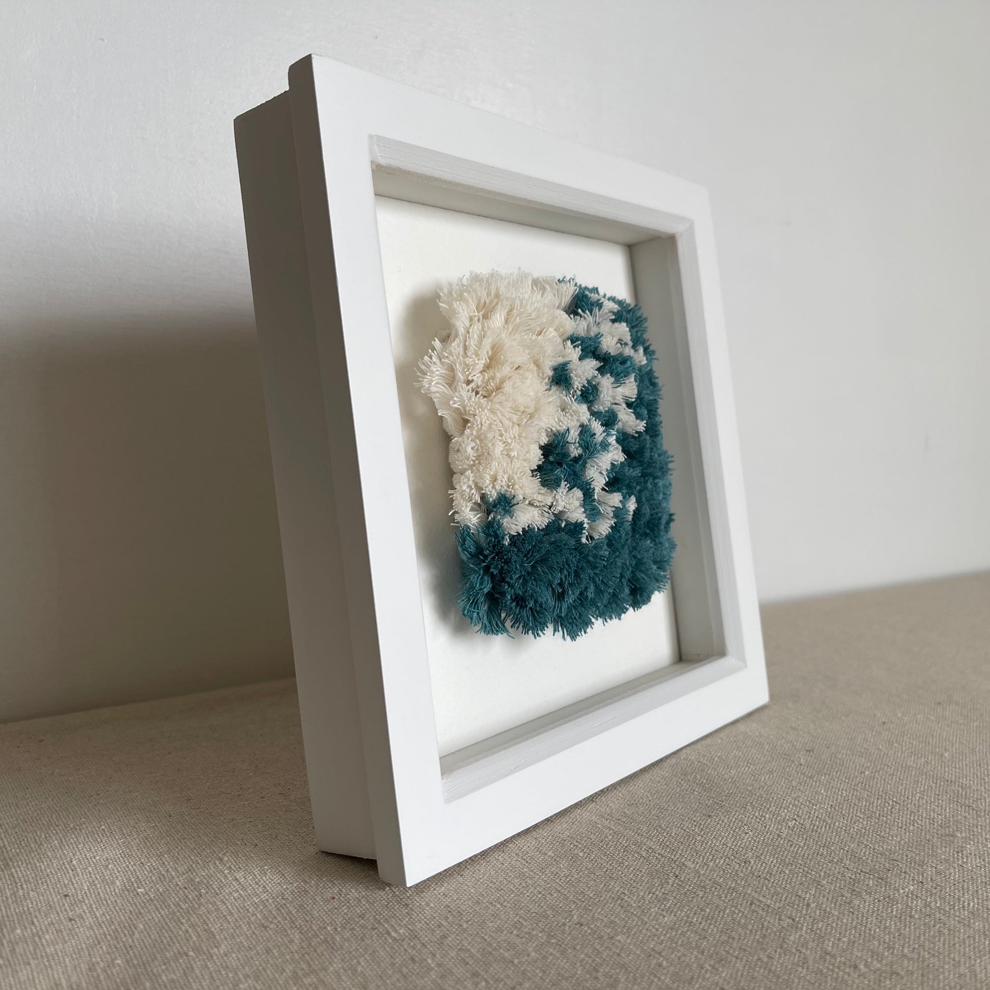 Ocean teal and cream fluffy textured woven art in a square white painted wood box frame