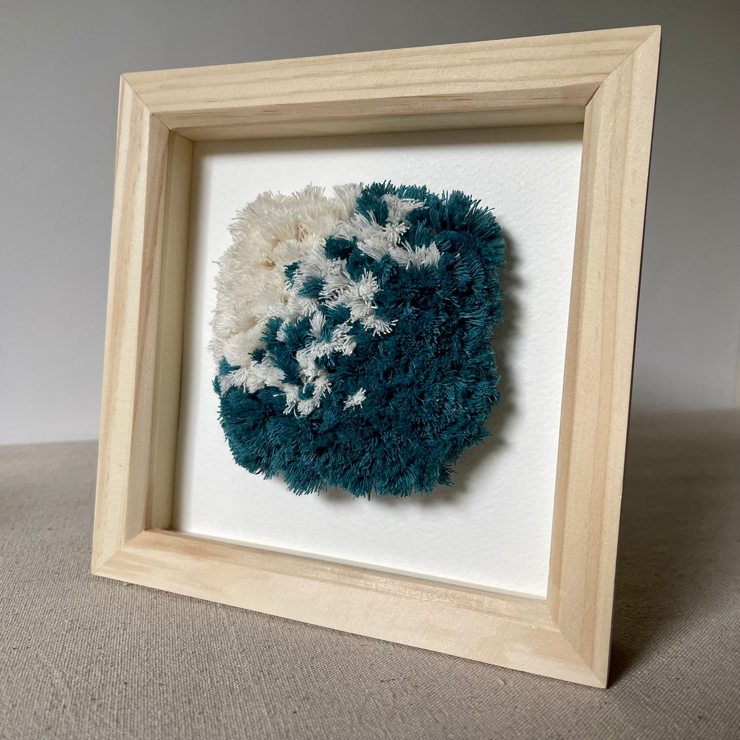 Ocean teal and cream fluffy textured woven wall art in a wood frame