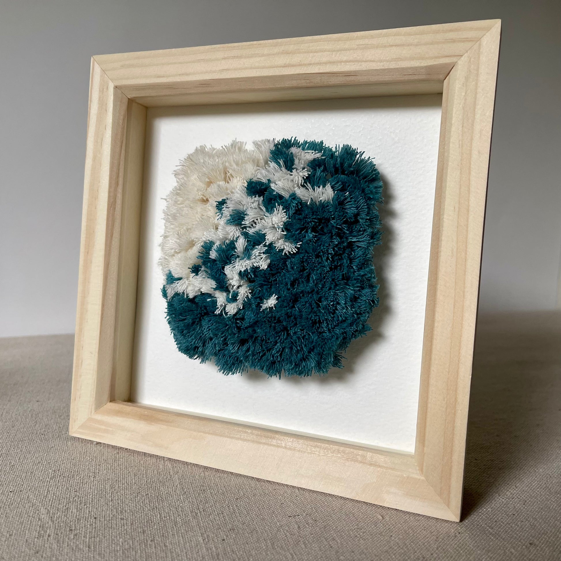Ocean teal and cream fluffy textured woven wall art in a wood frame