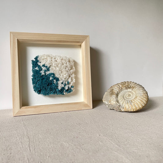 Square natural wood deep box frame housing a teal and cream fluffy textured woven textile art piece