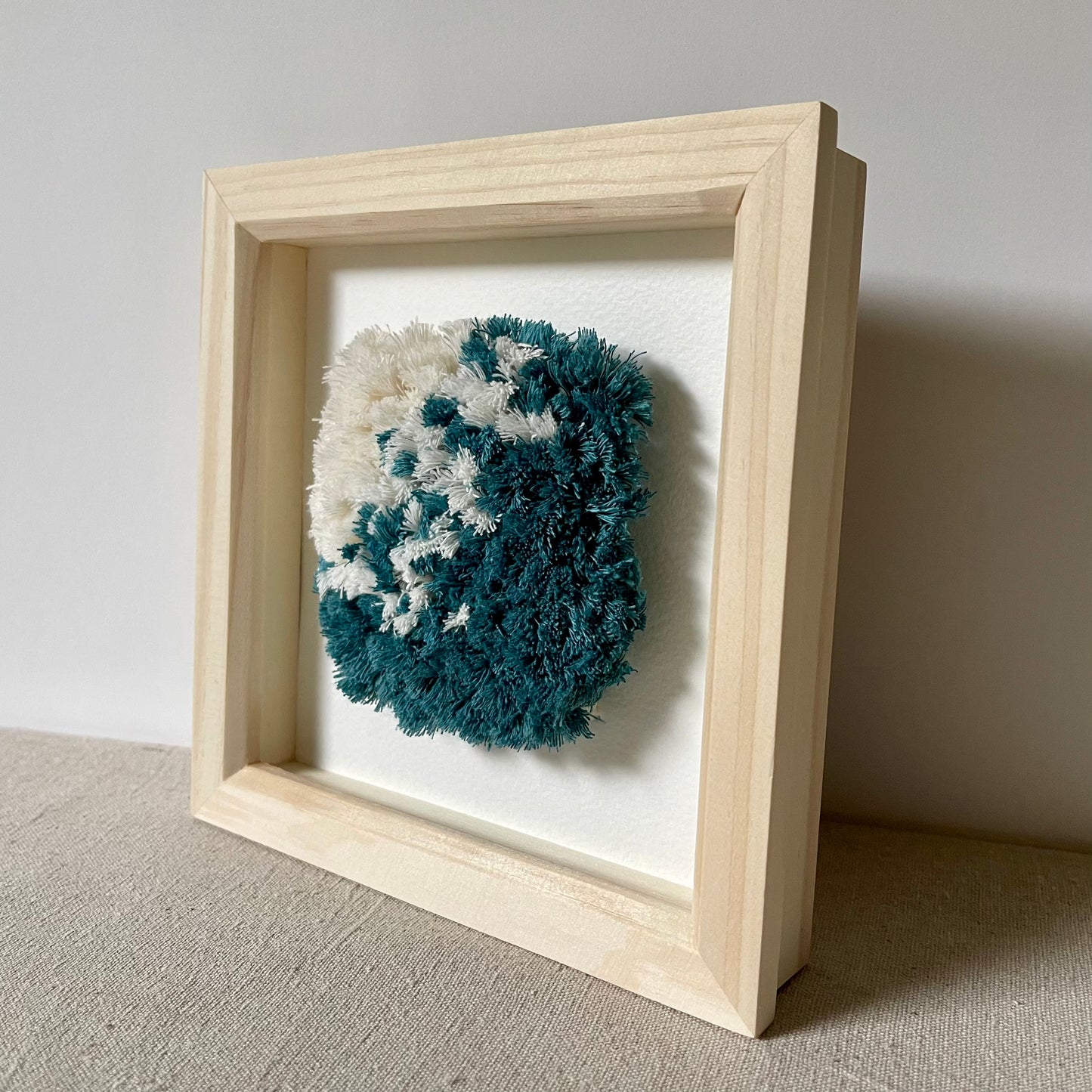 Ocean teal and cream fluffy textured woven wall art in a square wood frame